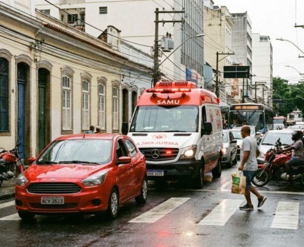 Motorista está parado no semáforo quando ambulância se aproxima com sirene ligada, condutor fica sem saber como abrir passagem e teme cometer outra infração ao invadir faixa de pedestres ou calçada, CTB explica o dever específico nessas situações
