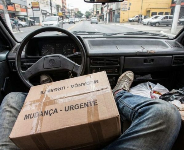 Motorista precisava levar uma caixa grande durante a mudança, ao perceber que não havia espaço nos bancos, decide apoiá-la entre as pernas enquanto dirige e é abordado por agentes que explicam o risco dessa improvisação